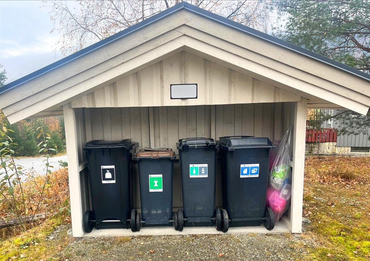 Avfallsskur med fire avfallsbeholdere og en plastsekk i - Klikk for stort bilde